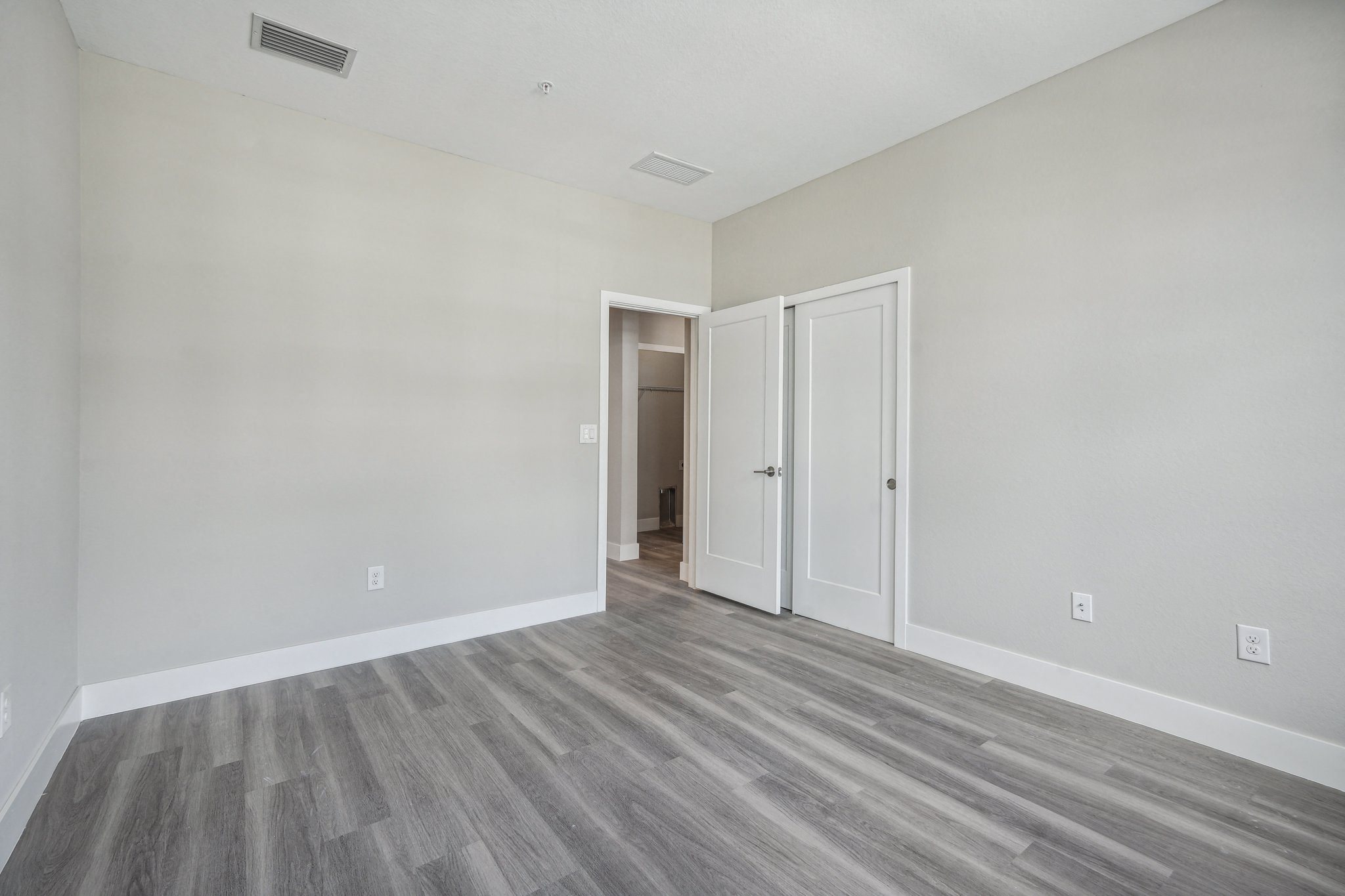 an empty bedroom with white walls and wood flooring